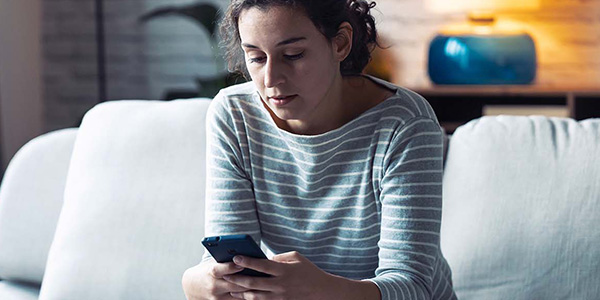 Woman sitting on couch looking at her mobile phone