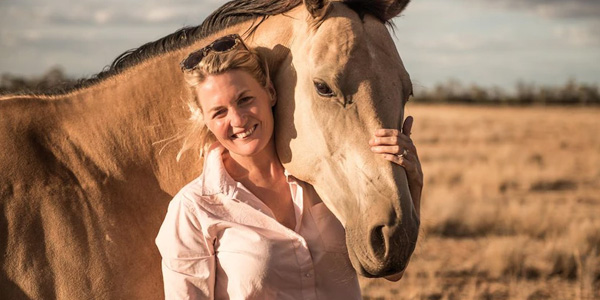 Smiling woman posing for a photo with a horse